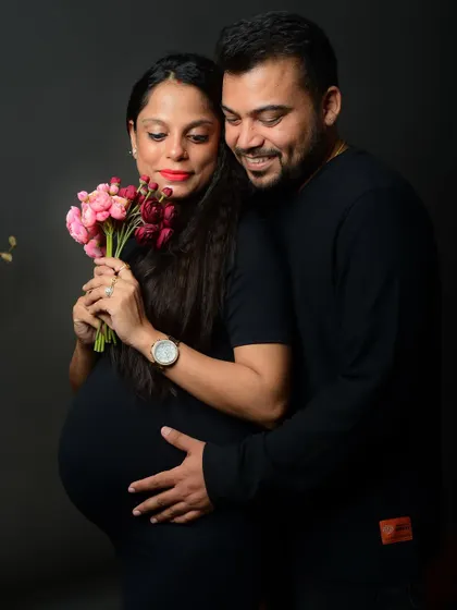 A beautiful, smiling portrait of the couple. The addition of the flower bouquet adds a touch of color and romance to the maternity photo.