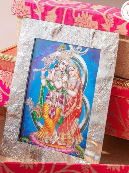 A timeless gift of a silver-plated photo frame featuring Radha and Krishna, perfect as a religious or traditional wedding favor.