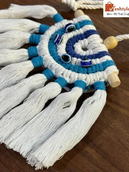 This angle highlights the concentric circles of the evil eye design, woven with dark blue, light blue, and white cotton cords.