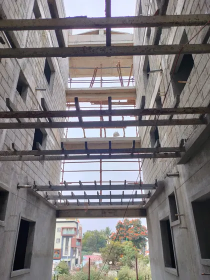 Looking up through the open atrium of a building under construction. The exposed concrete beams and floor slabs give a clear view of the multi-level structural design.