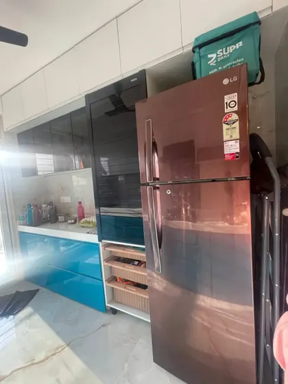 A real-life view of the completed blue parallel kitchen, showing how the client's appliances, like the stylish copper-tone refrigerator, integrate perfectly into our design.