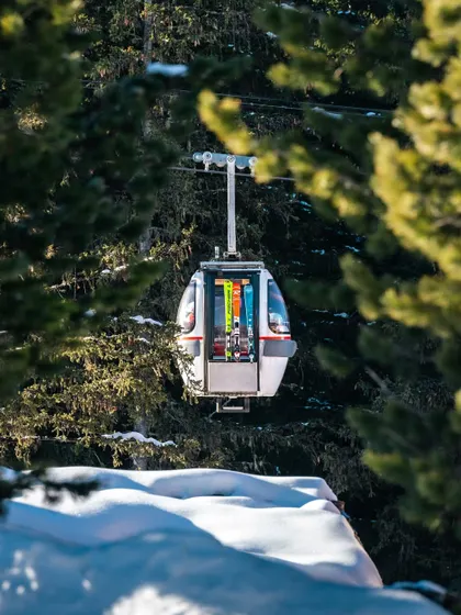A ski gondola framed by pine trees in the snow. I shoot in all seasons, capturing the unique atmosphere of a destination whether it's a sunny beach or a snowy mountain.