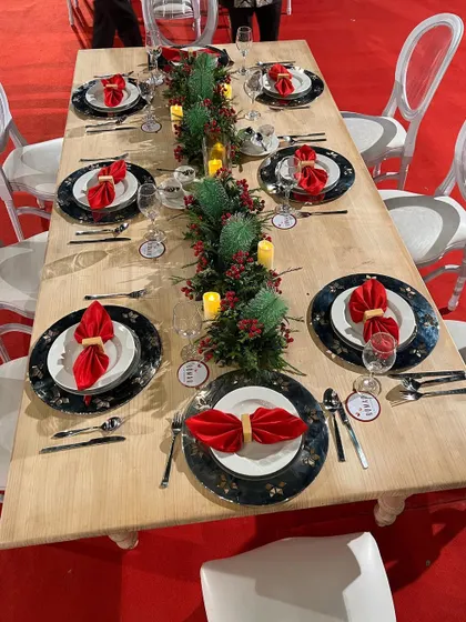 A festive Christmas-themed tablescape. We used a long wooden table, plates with a starry pattern, and a runner of pine branches and red berries to create a classic and elegant holiday dining setting.