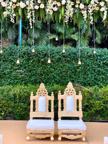 The ornate thrones for the bride and groom, set against a backdrop of hanging floral strings and temple bells.