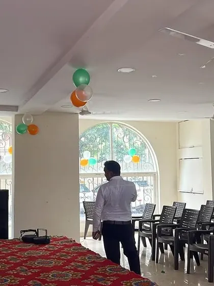 A view of the hall being set up for a corporate gathering, with seating arrangements and a simple stage with a sound system.