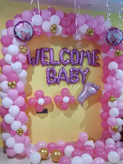 A clear, straight-on photo of the pink and white welcome baby decoration, showing the full arch and balloon details.