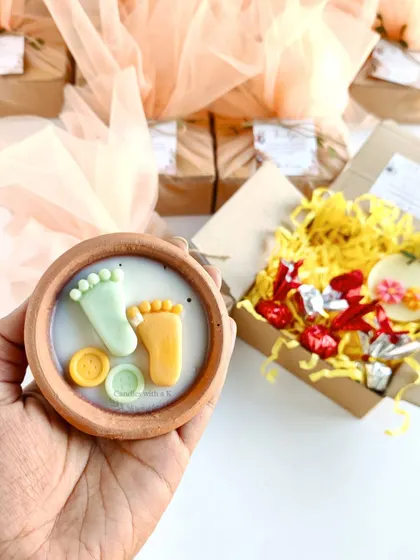 A custom baby shower gift box with a clay pot candle, soy wax sachet, and handmade chocolates.