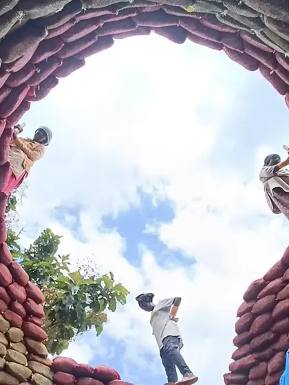 A view from below as women masons work on the upper layers of an earthbag dome. This perspective emphasizes the impressive scale of the structure they are creating.