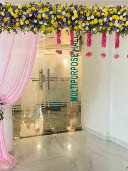 The entrance to a multipurpose hall decorated for an engagement with a colorful floral header and hanging garlands.