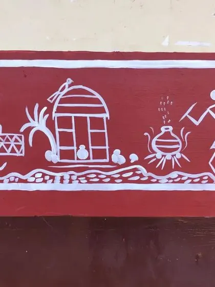 This panel depicts a scene of daily life. A figure sits weaving or preparing food, a hut with chickens is shown, and another person tends to a cooking pot, all rendered in the classic Warli style.
