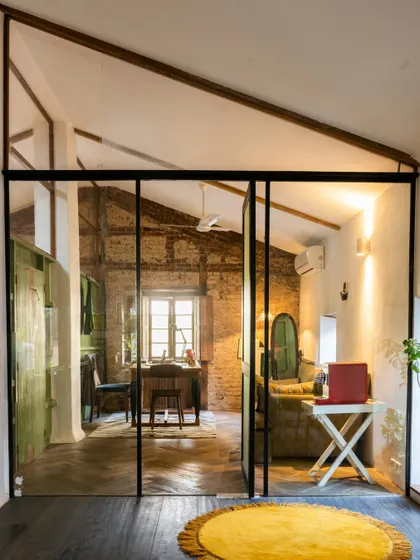 A view into my cabin through a modern glass partition. This shows how we balanced the raw, historic elements of the studio with contemporary design choices to create a space that is both a home for our creativity and a testament to the building's past.
