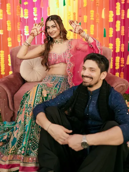 A playful pose from the couple during their Sangeet, showing off the bride's beautiful mehndi.