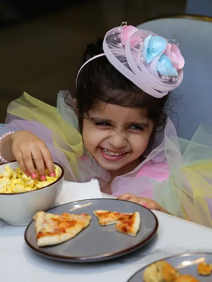 The birthday girl, Kyra, happily digging into some pizza and snacks at her party.