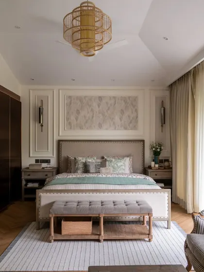 A full view of the classic and rustic master bedroom, featured in a publication. The symmetrical design, wall mouldings, and large rattan chandelier are highlighted as key elements of its timeless appeal.