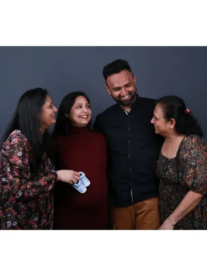 A happy family portrait where the couple, sister, and mother-in-law all share a loving look, celebrating the new baby on the way.