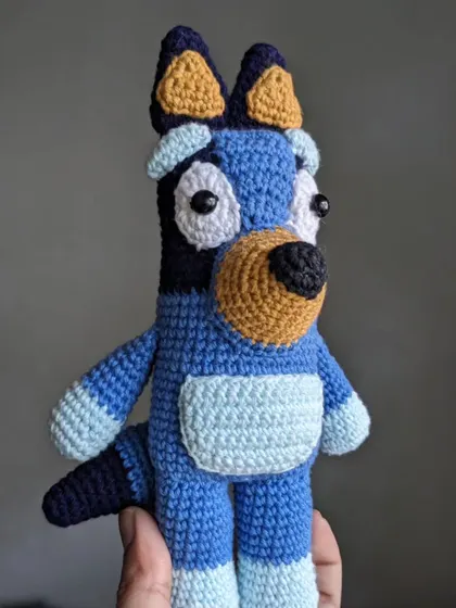 A side view of the Bluey crochet doll, showing his tail and body shape.