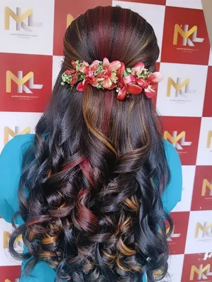 A half-up style on highlighted hair, featuring a colorful floral accessory that complements the hair color.