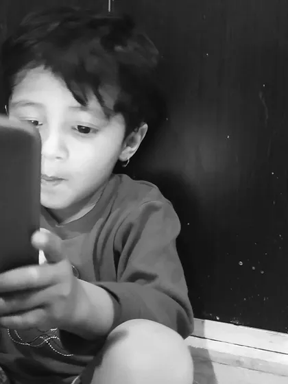 A young child completely absorbed in the world of a smartphone. This candid shot is an honest look at contemporary childhood, captured without any staging.