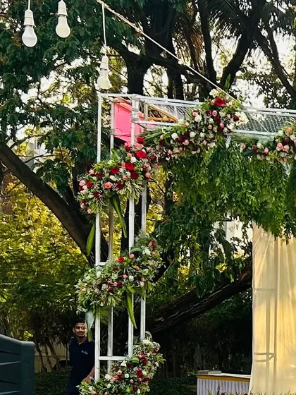 A side view of a floral arch for an outdoor stage, showing how the structure is decorated with cascading flowers and integrated into the garden setting.