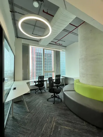 This corner meeting room at Kissflow takes full advantage of the building's architecture and city views. The curved sofa and flexible desk arrangement create a versatile space for informal team meetings.
