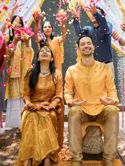 A beautiful moment of laughter and blessings during a Haldi ceremony, with guests showering the couple with colorful flower petals.