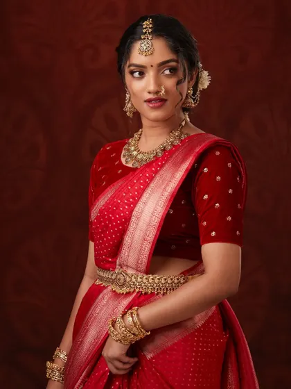 The side profile highlights the intricate jhumkas and hair accessories.