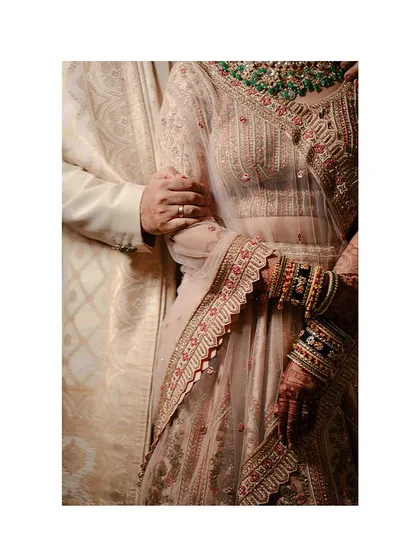 A close-up on the details: the bride's hand, adorned with bangles and henna, resting on the groom's arm. A simple, powerful symbol of their union.