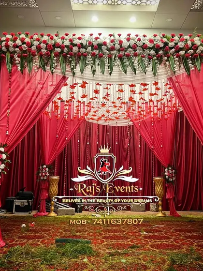 A beautiful Muhurtham mantapa designed with rich red velvet drapes, a canopy of red and white flowers, and hanging floral strings. This elegant setup creates a sacred and visually stunning space for the main wedding ceremony.