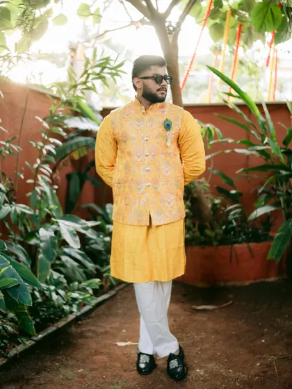 The groom strikes a cool pose in his sunglasses during the outdoor Haldi event.