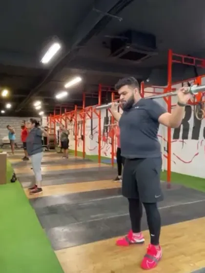 An athlete preparing for an overhead squat, a key assistance exercise for the snatch. This movement builds stability and confidence in the bottom of the catch position.