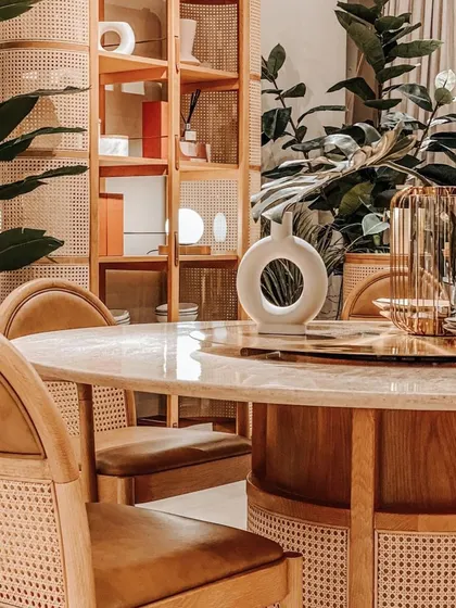 The Siena Dining Set, featuring a round travertine stone table, serves as a stunning centerpiece. The natural rattan and warm leather of the chairs create a look of tropical sophistication and timeless elegance.