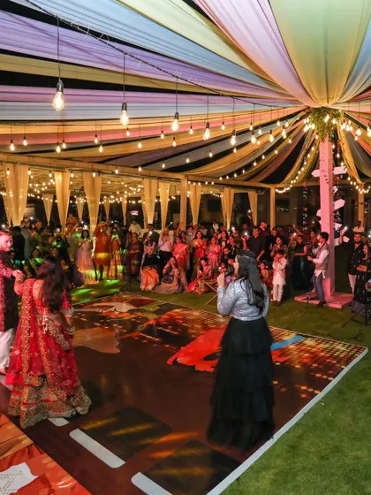 The energy of a Sangeet is infectious. Here, the couple and their guests enjoy the performances under a vibrant canopy of lights, creating a memory filled with music, laughter, and shared joy.