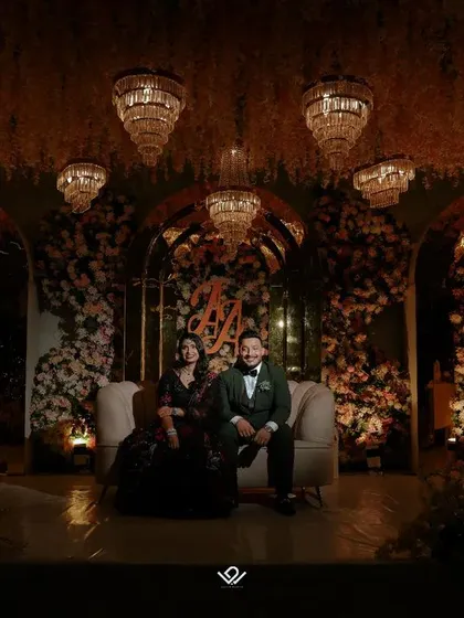 A wide, atmospheric shot of a couple on their reception stage, creating a sense of grandeur and romance.