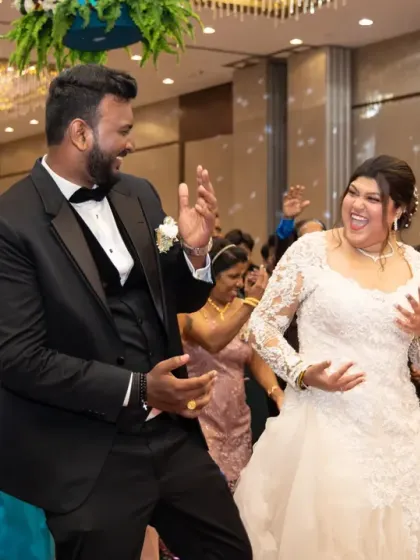 Pure happiness on the dance floor. This candid photo captures the bride and groom laughing and dancing together, surrounded by their loved ones.