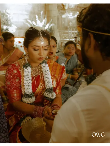 The bride participates in a wedding ritual, her expression serene and focused, capturing the solemnity of the moment.
