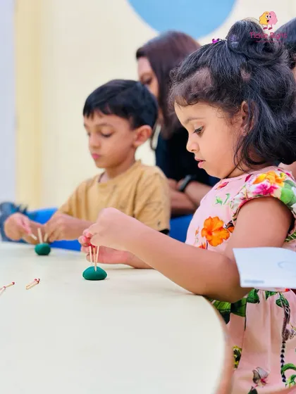 A girl works on a craft with playdough and paper clips, an activity that strengthens her pincer grasp and fine motor skills.