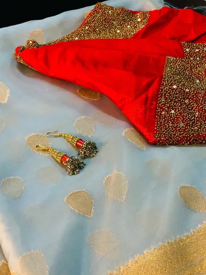 The complete look for our grey organza saree, paired with a heavily embroidered red blouse and handcrafted jhumkas.