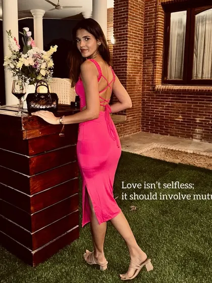 A reflective moment in a stunning pink backless dress. The vibrant color and daring silhouette make a statement, perfect for a special evening or a vacation dinner.
