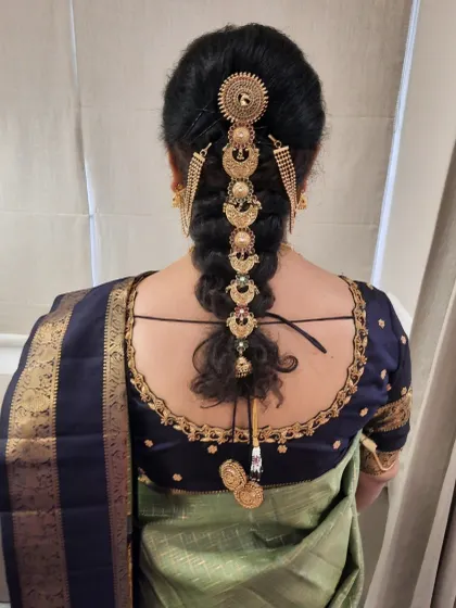 A detailed view of a traditional South Indian bridal braid. This hairstyle features a neat, tight braid decorated with exquisite gold-plated jada billalu, creating a timeless and regal look perfect for the main wedding ceremony.