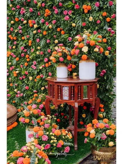 The vibrant floral arrangements against the green flower wall create a stunning visual contrast, making the Haldi decor truly stand out.