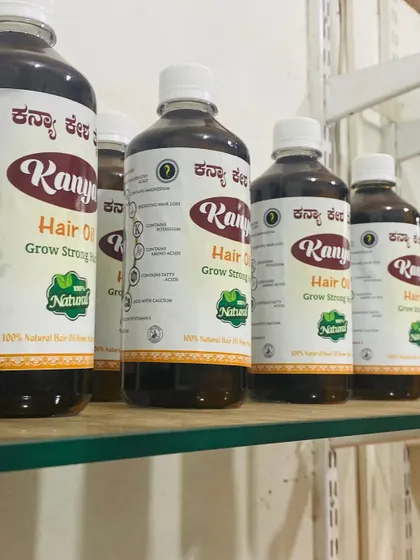 A side view of the larger Kanya Hair Oil bottles lined up on a shelf, showing the product label.