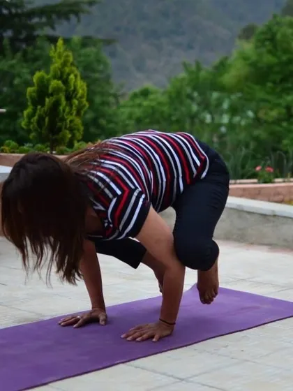 A student practices Bakasana, the crow pose, on a terrace overlooking the hills. The TTC is an opportunity to build strength and balance, both physically and mentally.