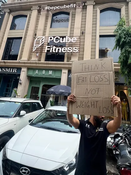 Our trainer stands proudly outside our building, holding a sign that reflects our core fitness philosophy.