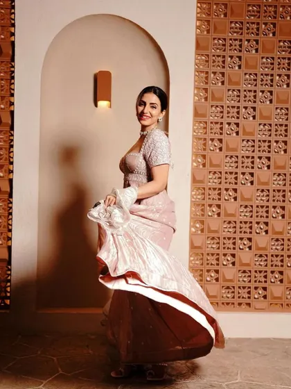 A full shot of celebrity Navina Bole, looking elegant in a dusty pink gown with a sleek bun and glamorous makeup.