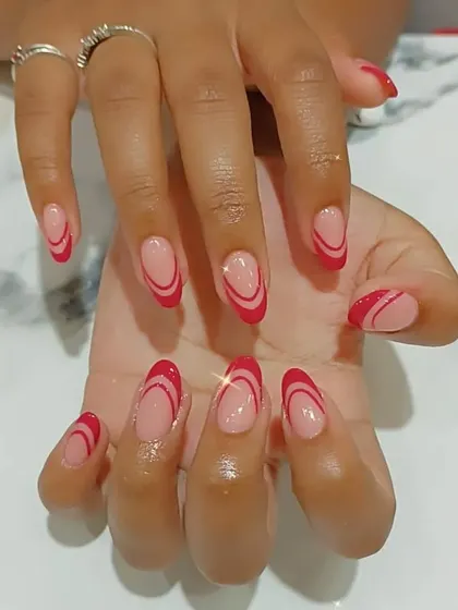 A modern and artistic take on a French manicure, using two shades of red to create abstract lines on a nude base.