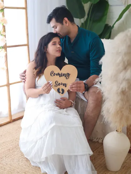 Using props like a "Coming Soon" sign adds a playful and personal touch to your couple's maternity shoot. It's a sweet way to announce your excitement.