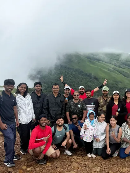 A group photo with the stunning, cloud-covered peaks of Kudremukha in the background. A classic Western Ghats trekking experience.