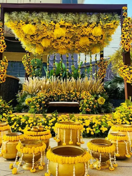 The Haldi ceremony setup complete with traditional brass pots (urlis) decorated with marigolds, all set against the stunning sunflower backdrop.