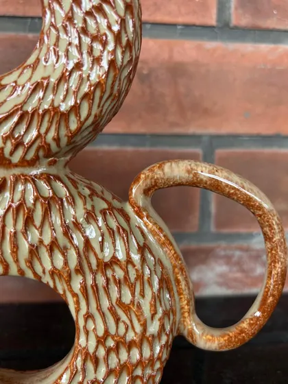 A close-up of a carved donut vase, showing the detailed texture and the rustic brown glaze.