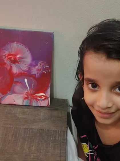 A young participant poses proudly next to her beautiful red and purple fluid art creation. It's so rewarding to see the confidence that making art can inspire.
